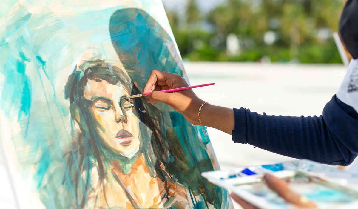 An artist painting a portrait at Kandima Maldives' KULA Art Festival